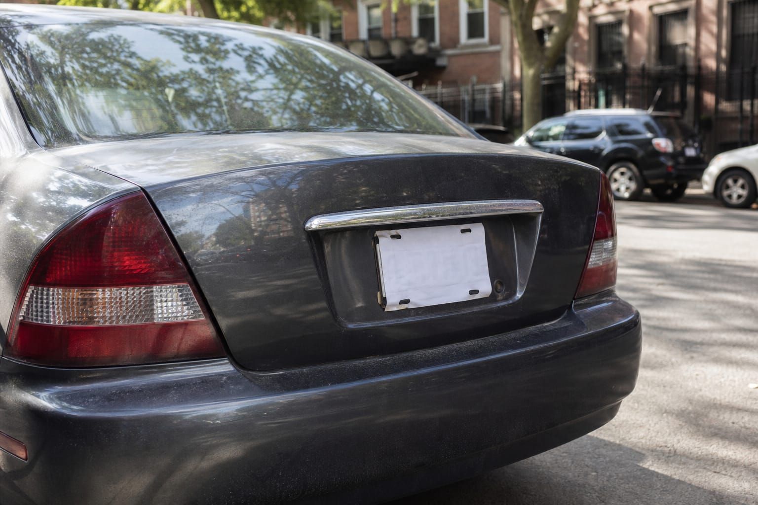 Voiture d'occasion garée dans une rue, plaque d'immatriculation provisoire visible à l'arrière
